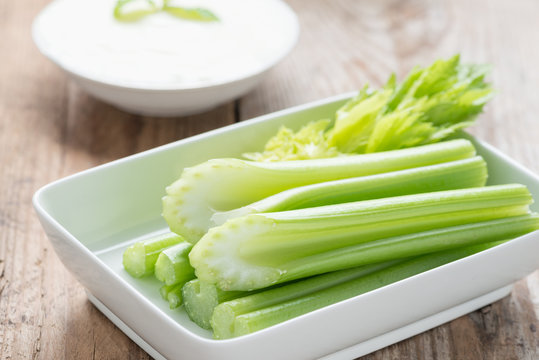 Fresh celery stick on white dish with yogurt.