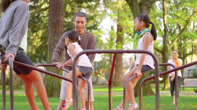Father pushing his daughters on a merry-go-round
