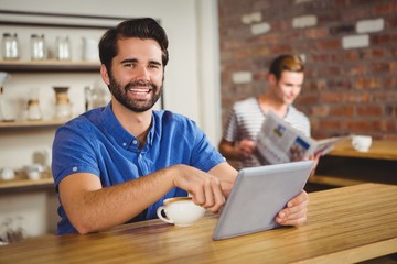 Fototapeta premium Young man having cup of coffee using tablet