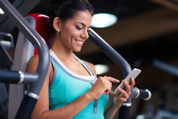 Woman using smartphone in fitness gym