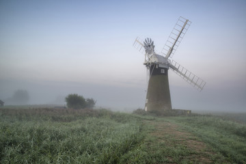 Windmill in stunning landscape on beautiful Summer dawn