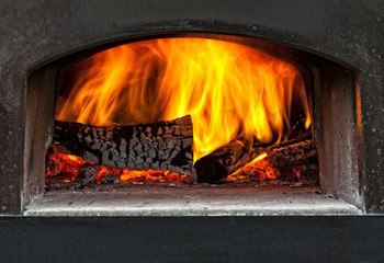 wood burning with flames in a traditional pizza oven.