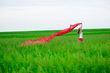 Young lady runing with tissue in green field. Woman with scarf.