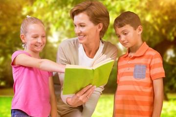 Composite image of teacher reading book with pupils at library