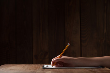 woman's hand writing on paper over wooden table