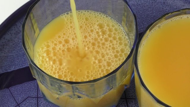 in a glass filled with orange juice on a blue plate
