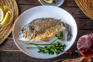 Fish food on white plate with lemon.
