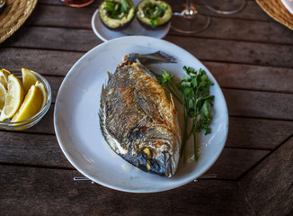 Fish food on white plate with lemon.