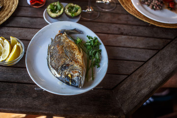 Fish food on white plate with lemon.
