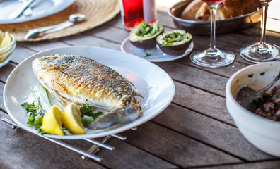 Fish food on white plate with lemon.