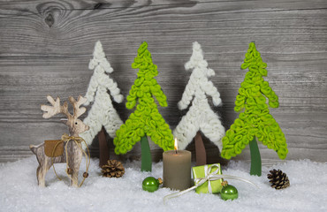 Dekoration zu Weihnachten mit Holz, Kerze und Rentier in apfelgrün, weiß, grau und braun.