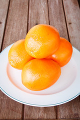 Orange on white plate put on wooden table.