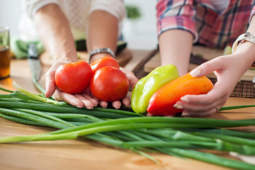 Women preparing dinner in a kitchen holding vegetables hands