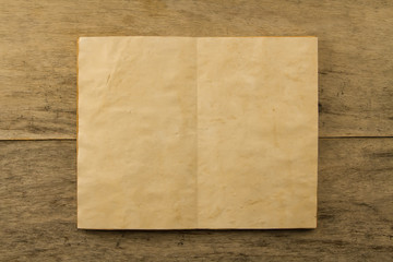 open old vintage book on the aged wooden background. Two clean sheet of paper.