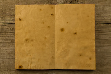 open old vintage book on the aged wooden background. Two clean sheet of paper.