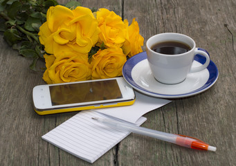 cup of coffee, phone, bouquet of roses and notebook with the handle