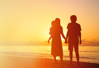 romantic couple with little child at sunset tropical beach