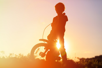Obraz na płótnie Canvas little boy riding bike at sunset