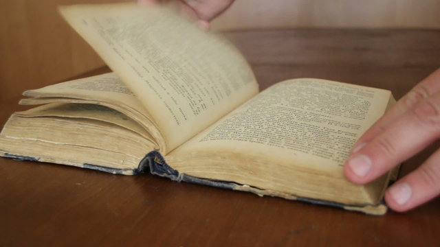 A man's hand turning on pages on some book.