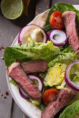 Mexican tortillas with green fresh salad filling, beef, onions, tomatoes with gucamole and tortilla chips on te vintage board