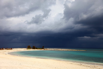 Fototapeta na wymiar Sunny beach, dark clouds and turquoise water. Paradise Island, Bahamas