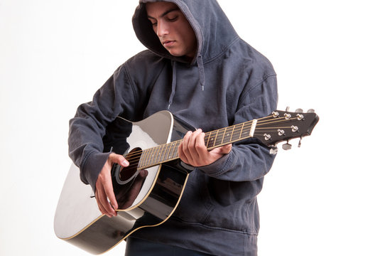 Young man dressed  in hoodie try to understand how to play acous