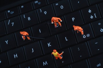 miniature di operai al lavoro sulla tastiera di un pc portatile