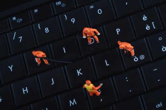 miniature di operai al lavoro sulla tastiera di un pc portatile