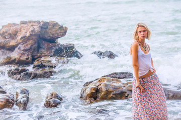 Beautiful young blonde woman posing outdoor at the rocky sea shore