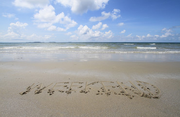 Word "WEEKEND" handwritten in sand on a beach