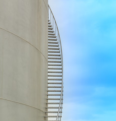Staircase on big fuel tank on blue sky background