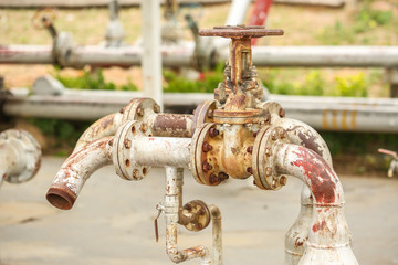 Rusty metal pipes and hand valves in fuel tank station