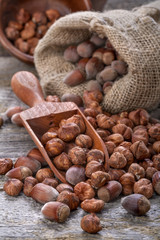 Hazelnuts on a spoon and in a linen sack on an old wooden table