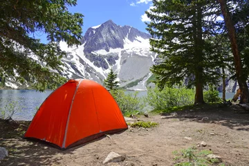 Schilderijen op glas Camping tent in the mountains with lake and snow capped peaks © nyker