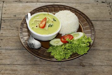 Thai green curry soup and some rice decorated on wooden background, Thai food.