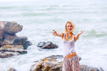 Beautiful young blonde woman posing outdoor at the rocky sea shore