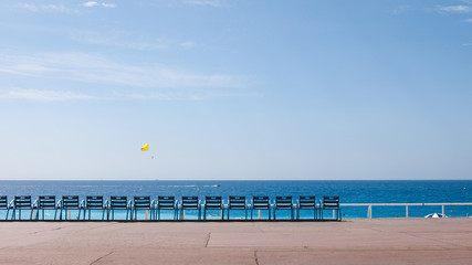 Set of blue chairs on the boulevard by the beach in Nice
