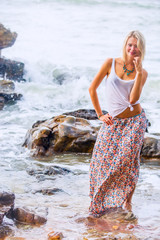 Beautiful young blonde woman posing outdoor at the rocky sea shore