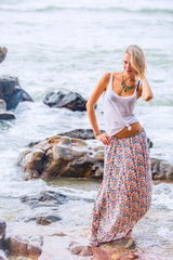 Beautiful young blonde woman posing outdoor at the rocky sea shore