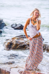 Beautiful young blonde woman posing outdoor at the rocky sea shore
