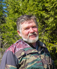 Fototapeta premium Portrait of a hunter with a gray beard on a background of green