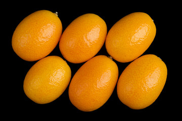 Oblique oval kumquats closeup. Macro photo from above on black background.