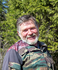 Fototapeta premium Portrait of a hunter with a gray beard on a background of green