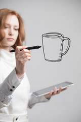 young woman draws a Cup of coffee on grey background