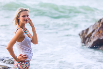 Beautiful young blonde woman posing outdoor at the rocky sea shore