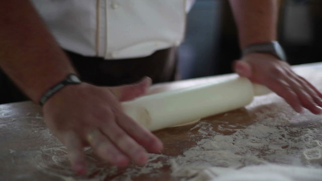 cook prepares the dough with a rolling pin.