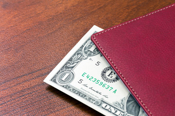 Notebook with dollars on a wooden table with place for text