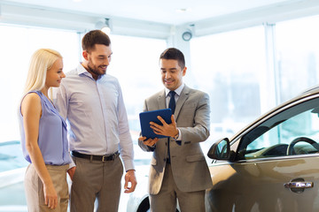 happy couple with car dealer in auto show or salon