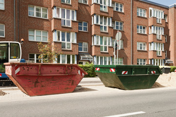 Fototapeta na wymiar Ein roter und ein grüner Container stehen vor einem Wohnhaus