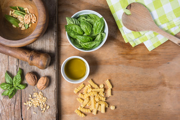 Making pasta with pesto with the original recipe of Genova. Wooden background and accessories communicate the sense of Italy.